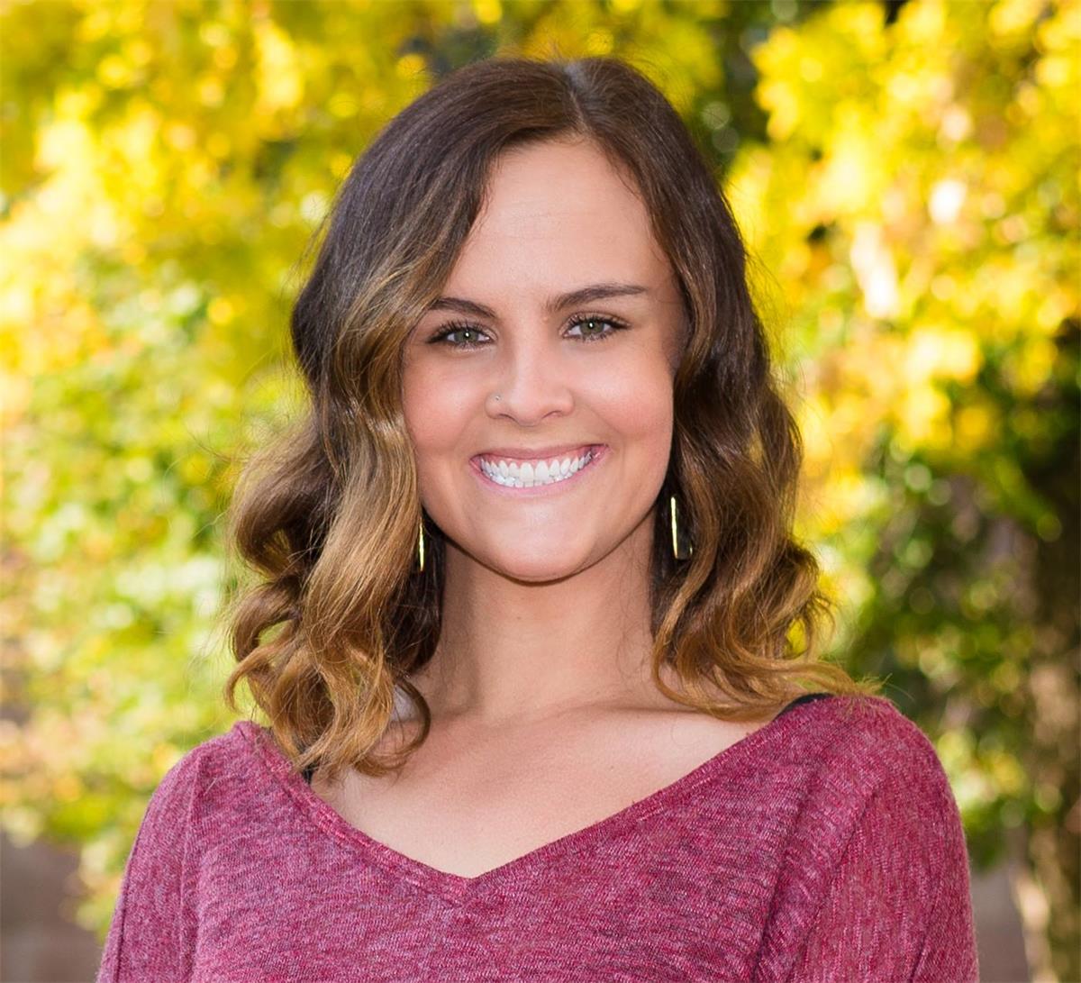 portrait of Sloane against a yellow-leafed tree